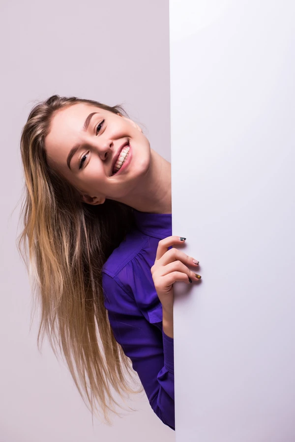 beautiful-woman-holding-blank-billboard-isolated-white-wall beautiful woman smiling after teeth whitening